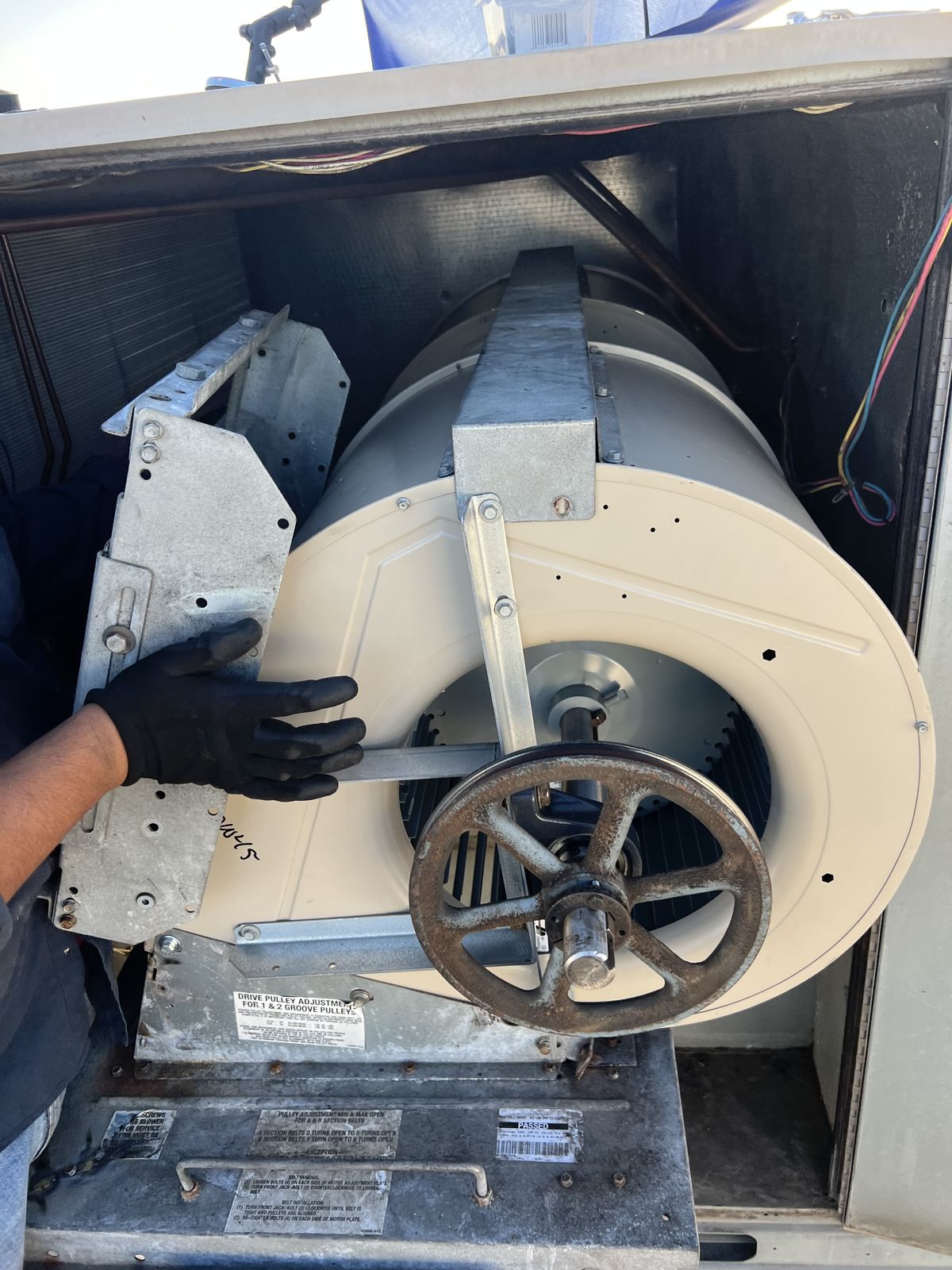 Guardian Air technician servicing a blower wheel assembly on a commercial HVAC unit